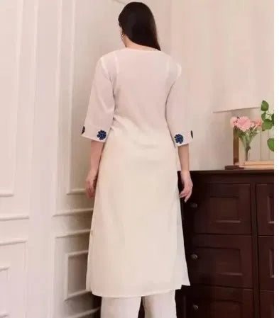 Woman wearing cream rayon kurti set with blue ethnic embroidery, premium fabric finish.
