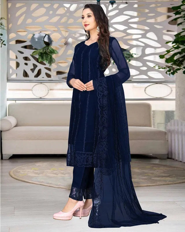 Woman wearing premium navy blue ethnic suit with sheer dupatta and elegant embroidery, showcasing fine fabric quality.