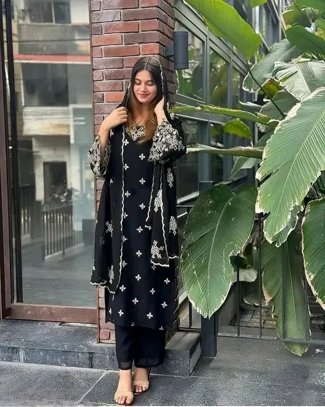 Woman wearing premium black rayon kurti set with white ethnic embroidery, standing outdoors.