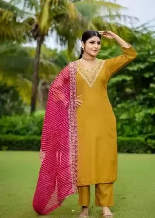 Woman in mustard ethnic suit with premium embroidery and vibrant pink dupatta outdoors