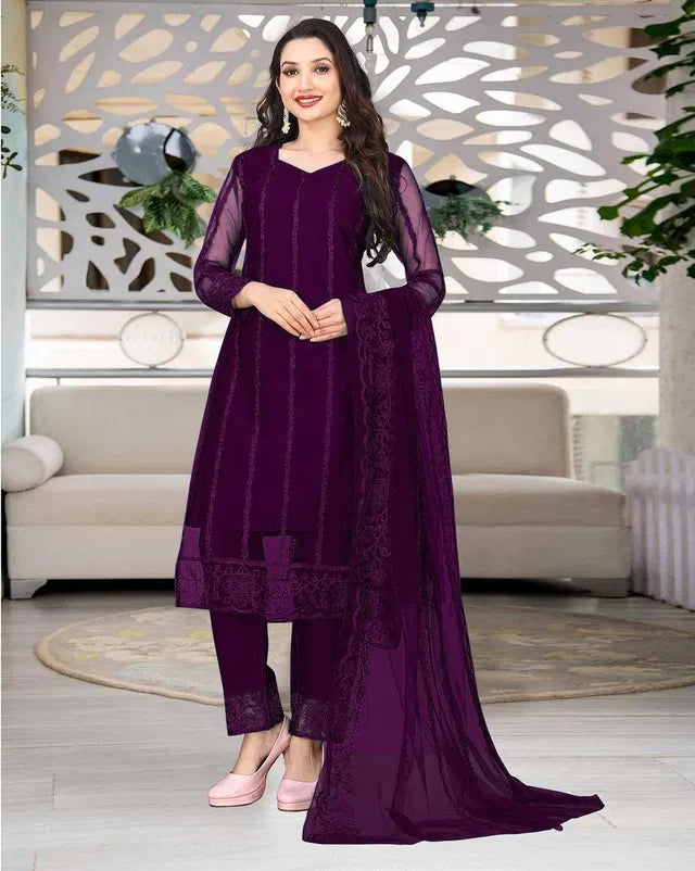 Woman in a premium purple ethnic suit with sheer sleeves and intricate embroidery.