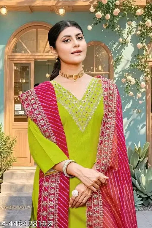 Woman in premium green ethnic suit with intricate embroidery, magenta dupatta, and elegant jewelry