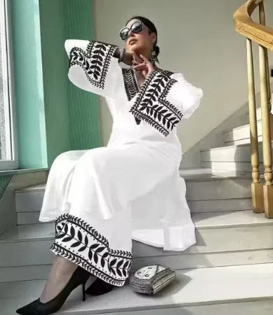 Woman in premium white rayon kurti set with black ethnic embroidery, seated indoors.